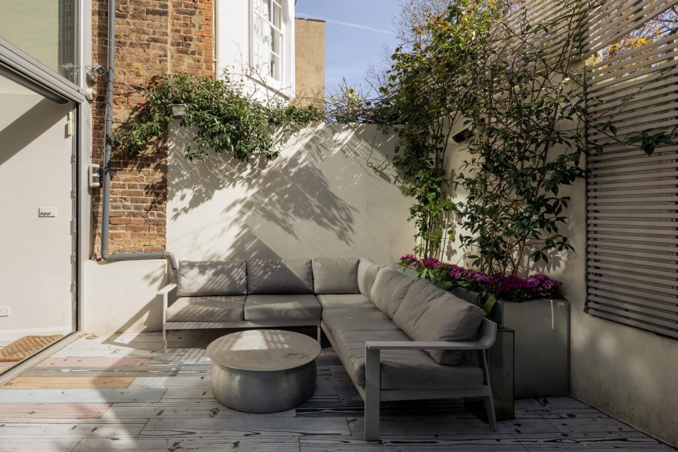 Outdoor seating area in a London garden with sofa and coffee table at Hornsey Lane, Highgate, N6.