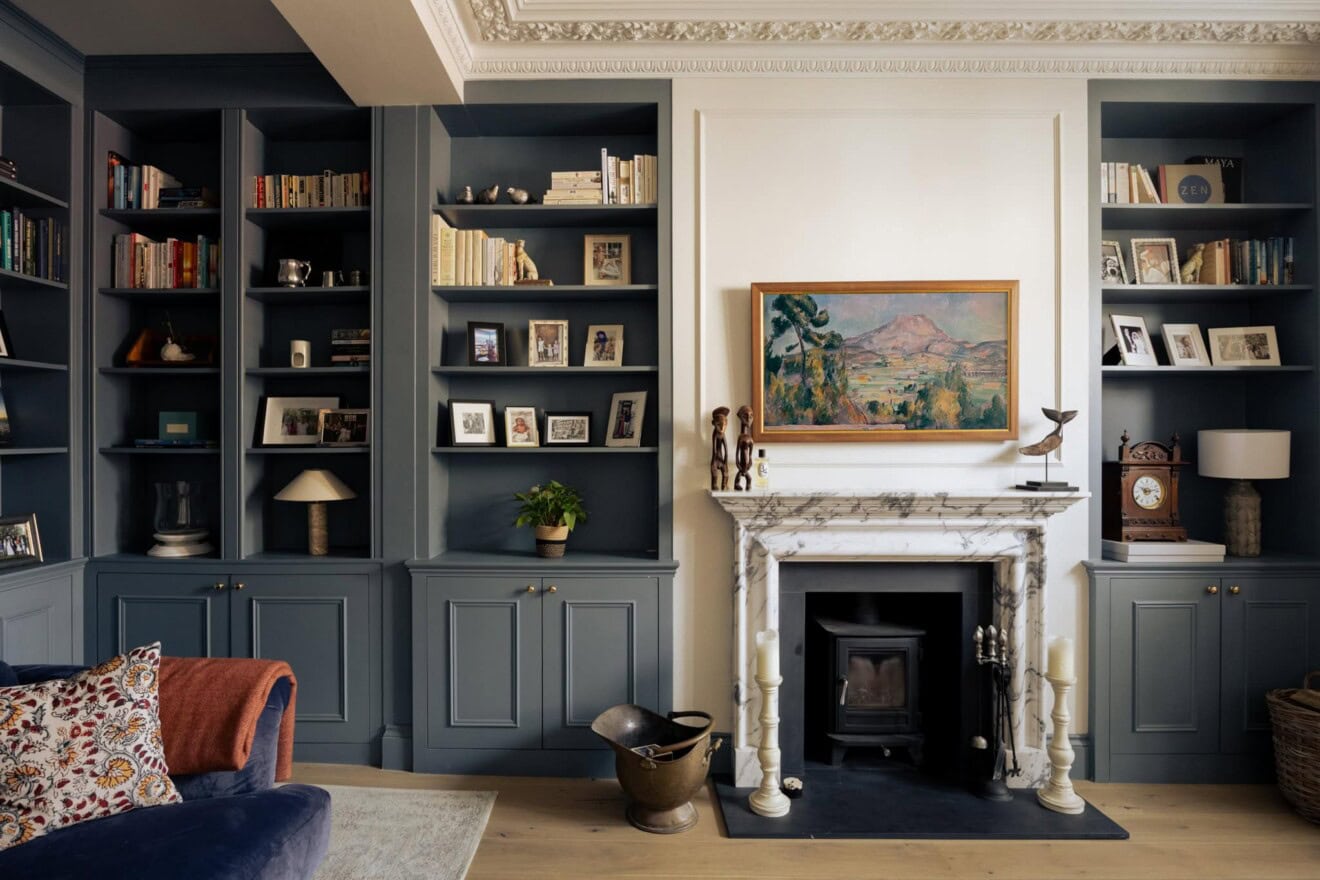 Interior of a stylish living room featuring dark blue bookshelves and a marble fireplace in Ravenswo.